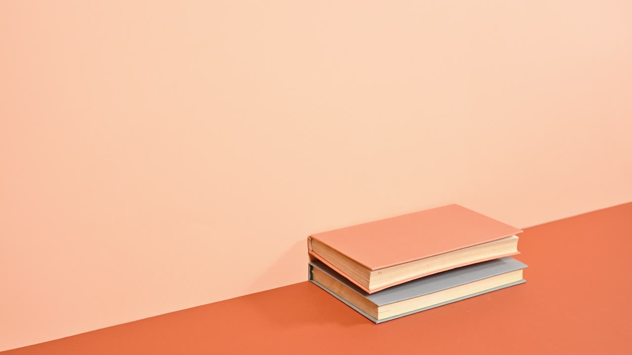 Stack of hardcover books ordering one on other on deep and bright orange theme. Stop motion