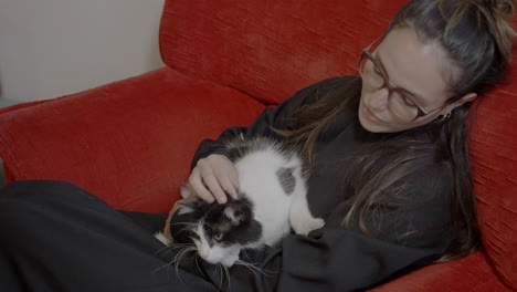 beautiful latina with her cat on red couch having a leisure time