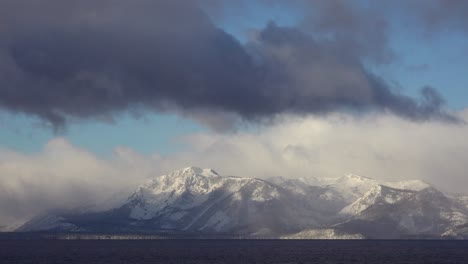 a time lapse shot of clouds moving over the snow covered mountains of lake tahoe in winter