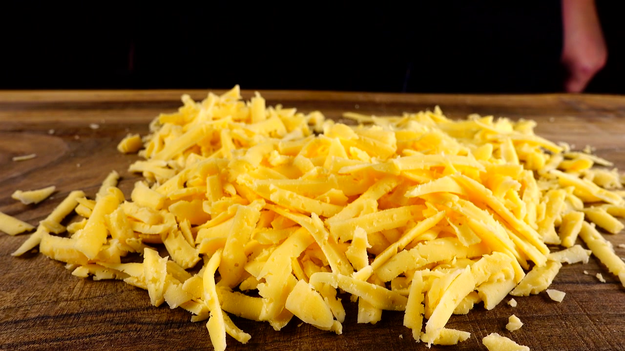 Lo chef strofina formaggio grattugiato su un tagliere