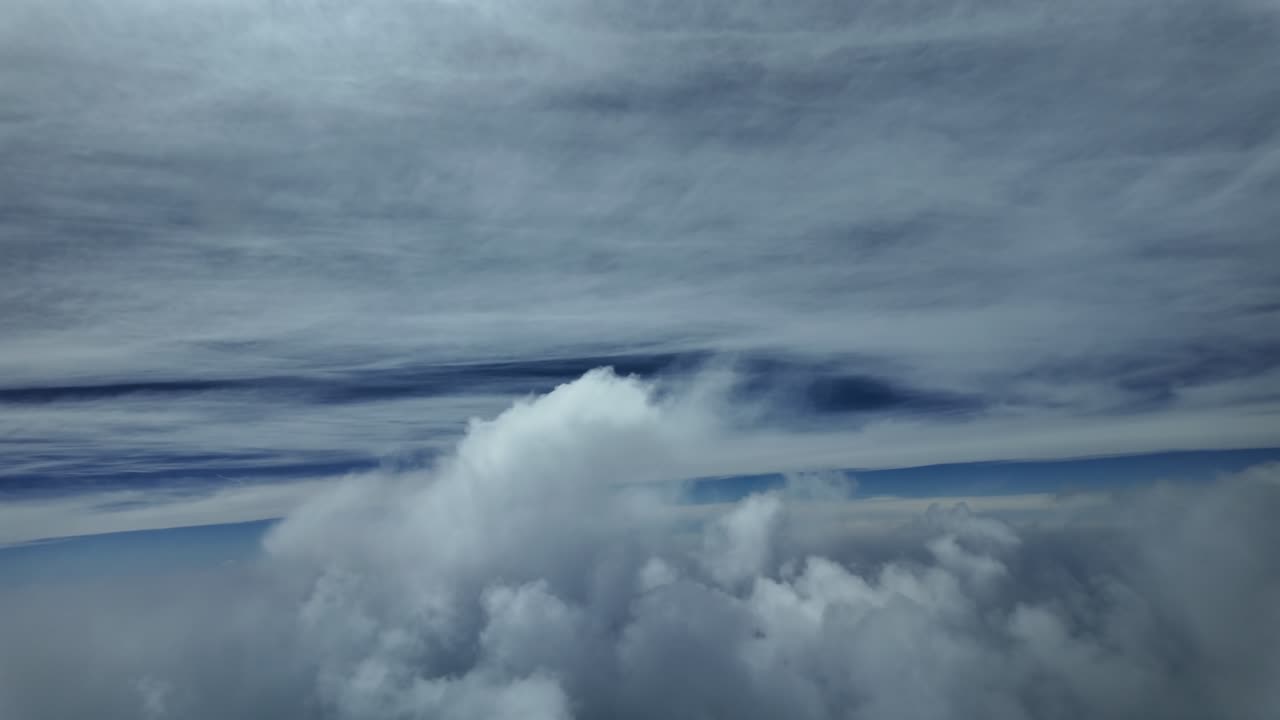 An immersive aerial view from inside a jet cockpit while flying at sunset through ethereal clouds under a deep blue sky.