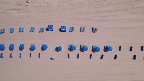 Vista-Aérea-De-La-Playa-Con-Sillas-Y-Sombrillas-Azules-Agua-Azul-Cielo-Azul-Palmeras-Ft