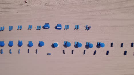 vista aérea de la playa con sillas y paraguas azules agua azul cielo azul palmeras ft