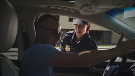 angry driver speaking with police officer upset man hitting steering wheel and talking angrily with woman in police uniform during driver license check