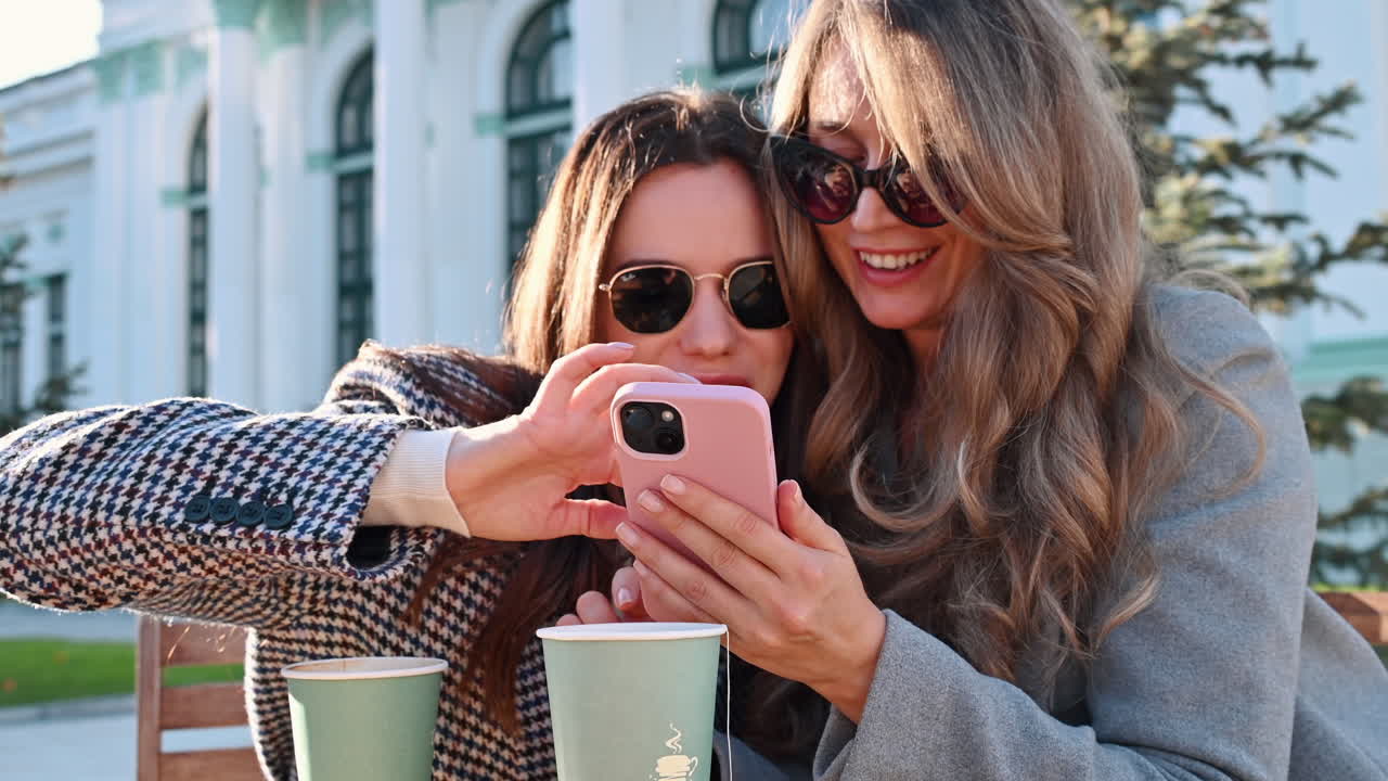 Two women going through a phone at a terrace