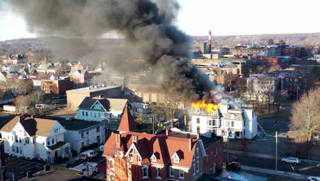 wide aerial approach shot of a burning building in new haven, connecticut on a sunny day