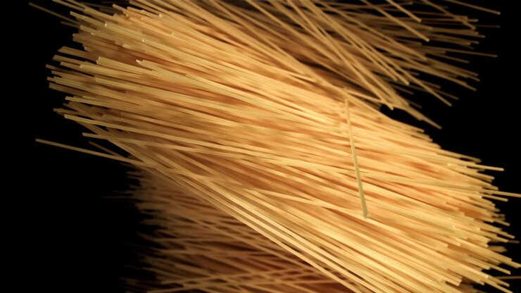 Spaghetti crudi che cadono al rallentatore su sfondo nero
