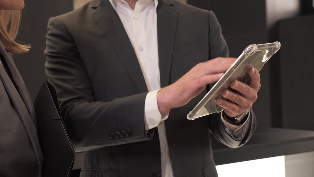 близкий вид бизнесмен с планшетом в офисной комнате. высококвалифицированные бизнес-партнеры рассматривают стартовый проект на современном цифровом устройстве во время встречи. женщина указывает пальцем на экран гаджета.