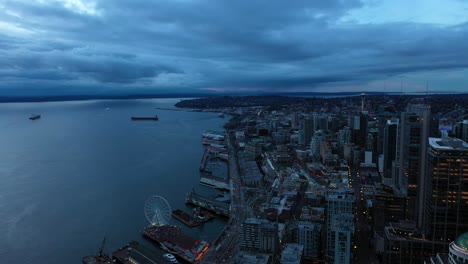 aerial pulling away from seattle's waterfront corridor on a dark and cloudy morning