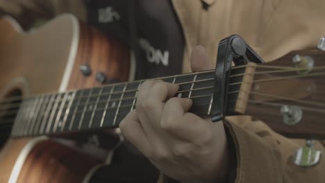 el joven canta y toca la guitarra acústica, el primer plano se inclina hacia abajo de la cara a las manos