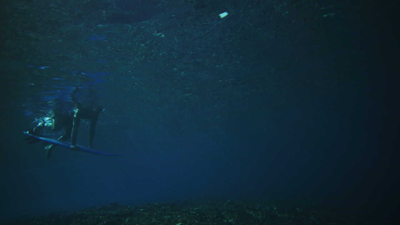 pan a través de la persona empujando la tabla bajo el agua pato buceo como la energía de la ola poderosa pasa por encima