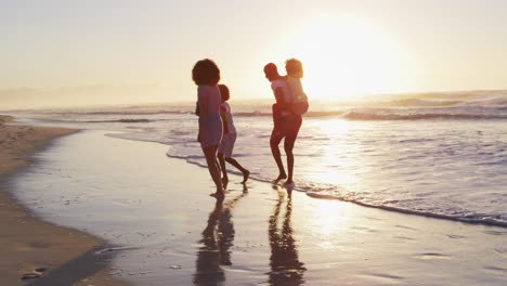 Afroamerikanische-Familie,-Die-Bei-Sonnenuntergang-Am-Strand-Gemeinsam-Spaß-Hat