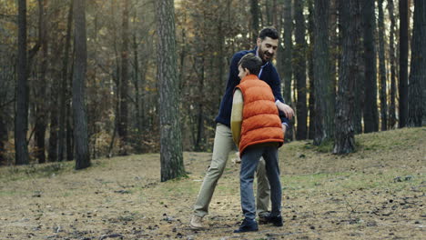 Caucasian-handsome-man-playing-with-his-little-cute-son-with-a-wooden-plane-in-the-forest