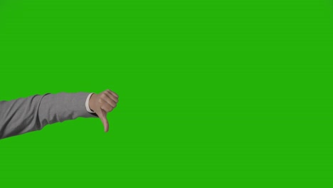 close up of arm of businessman in suit giving thumbs down gesture against green screen