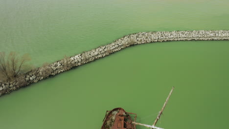 rusty red shipwreck stuck in shallow green water