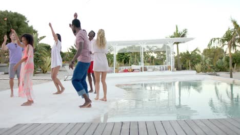 Happy-diverse-group-of-friends-dancing-with-sparklers-at-swimming-pool