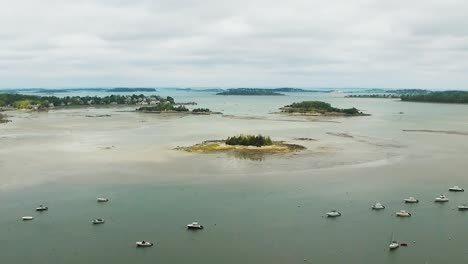 aerial view of a coastal new england harbor revealing islands, watercraft and city in the distance