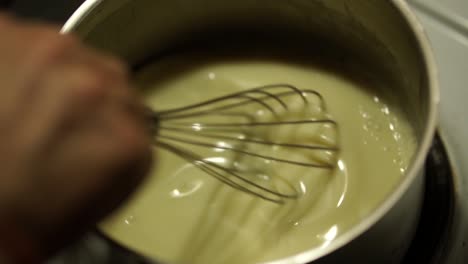 stirring creamy sauce in a small pan with the metallic whisk, still, slomo