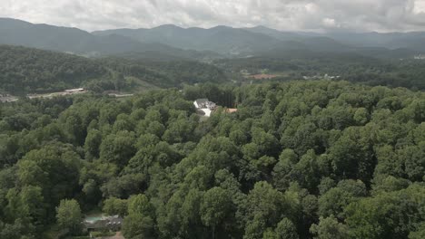 aerial flight over dense green se forest to rural home in smoky mtns