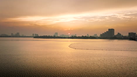 drone flying over west lake or ho tay at sunset with hanoi in background, vietnam