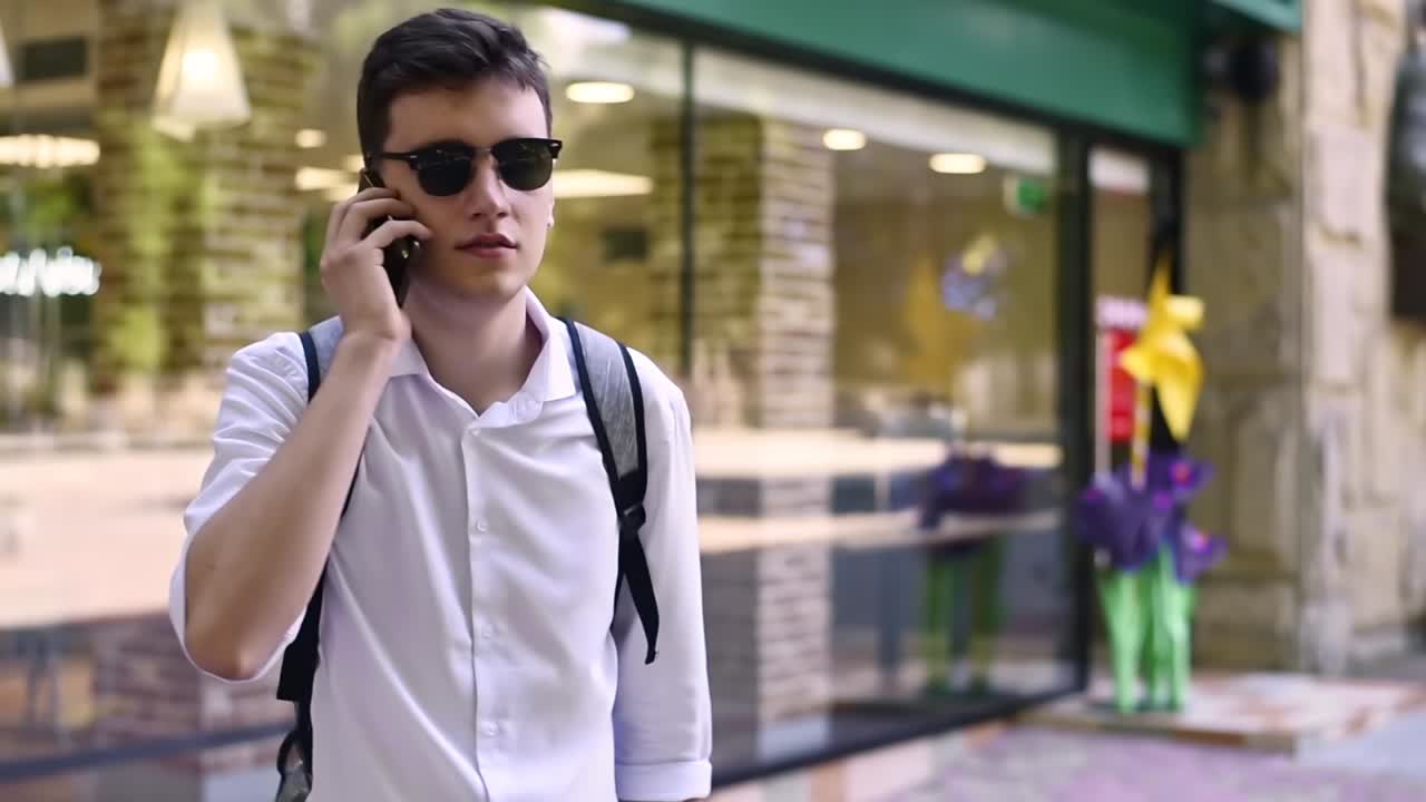 Caucasian man in white shirt and sunglasses talking on the phone. Sunny day