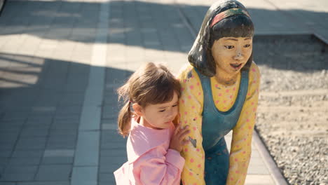 niña pequeña abraza estatua de niño coreano en la ciudad ferroviaria de gyeongamdong al atardecer
