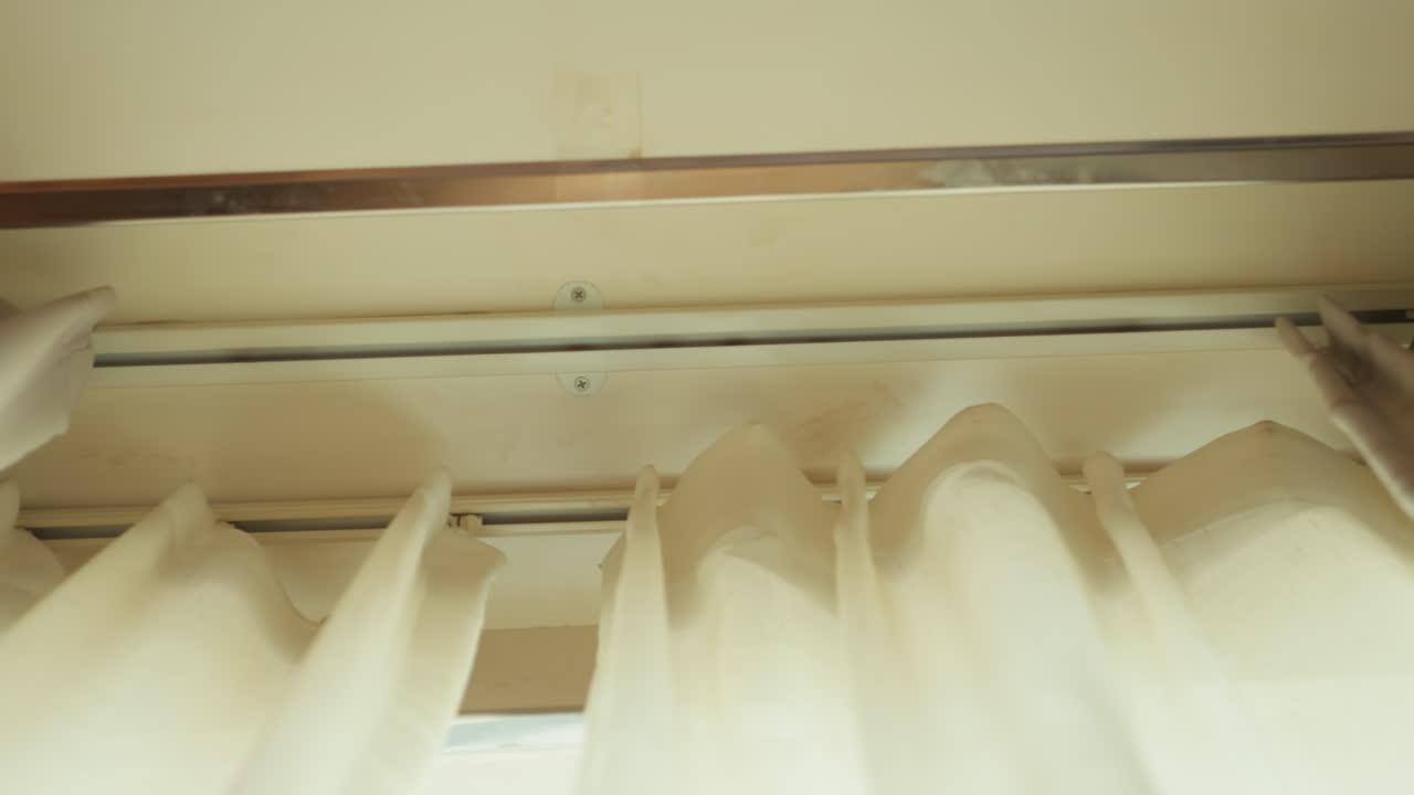 Sterk morgensol skinner mykt gjennom delikate gardinstoffer. Stille hotellsuite badet i tidlig morgenlys som filtreres gjennom gjennomsiktige gardiner og skaper en rolig atmosfære.