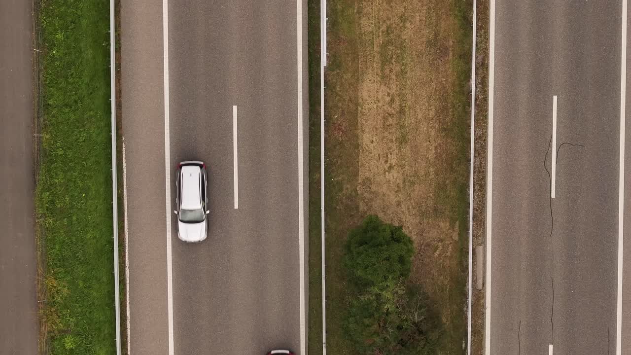 A top-down aerial view capturing a busy highway filled with passing cars. The motion of traffic flows seamlessly along the road, emphasizing urban connectivity and transportation efficiency.
