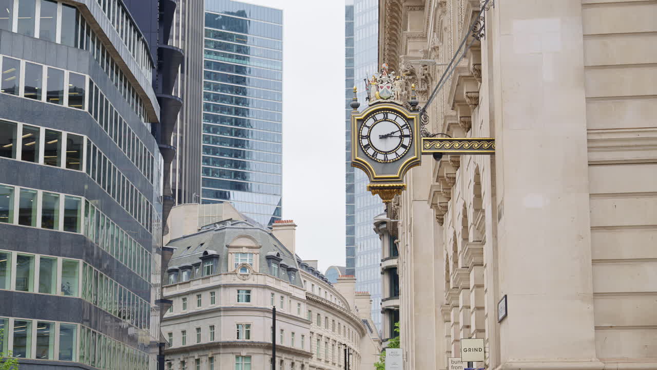 Close-up of a decorative white and gold clock mounted on a historic stone building in London, England