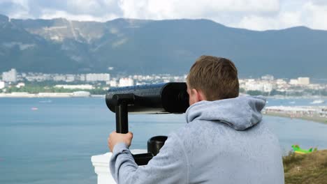 man looking through binoculars at scenic view