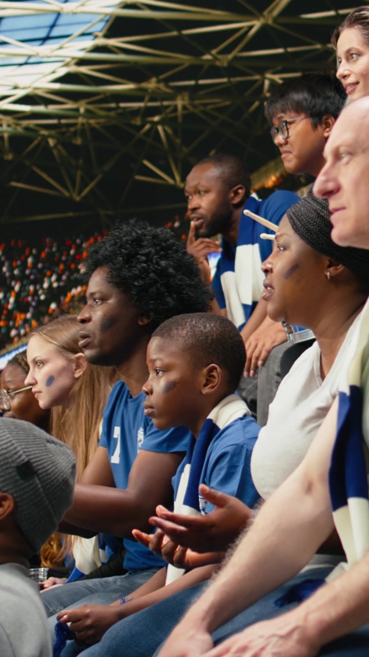 Video vertical: Aficionados al fútbol de varias generaciones viendo un momento de tensión desde las gradas del estadio