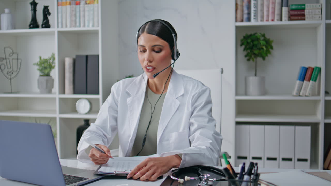 Healthcare physician consulting headset making notes at clinic workplace closeup
