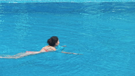 una joven sensual relajándose en la piscina.
