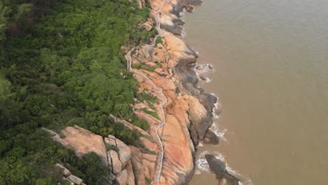 Top-down-view-following-along-rocky-coastal-trail-in-Coloane,-Macau