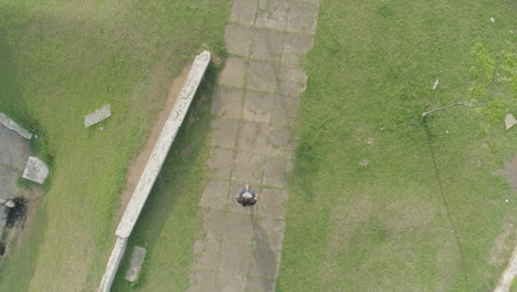 aerial follows man walking on pathwalk surrounded by grass