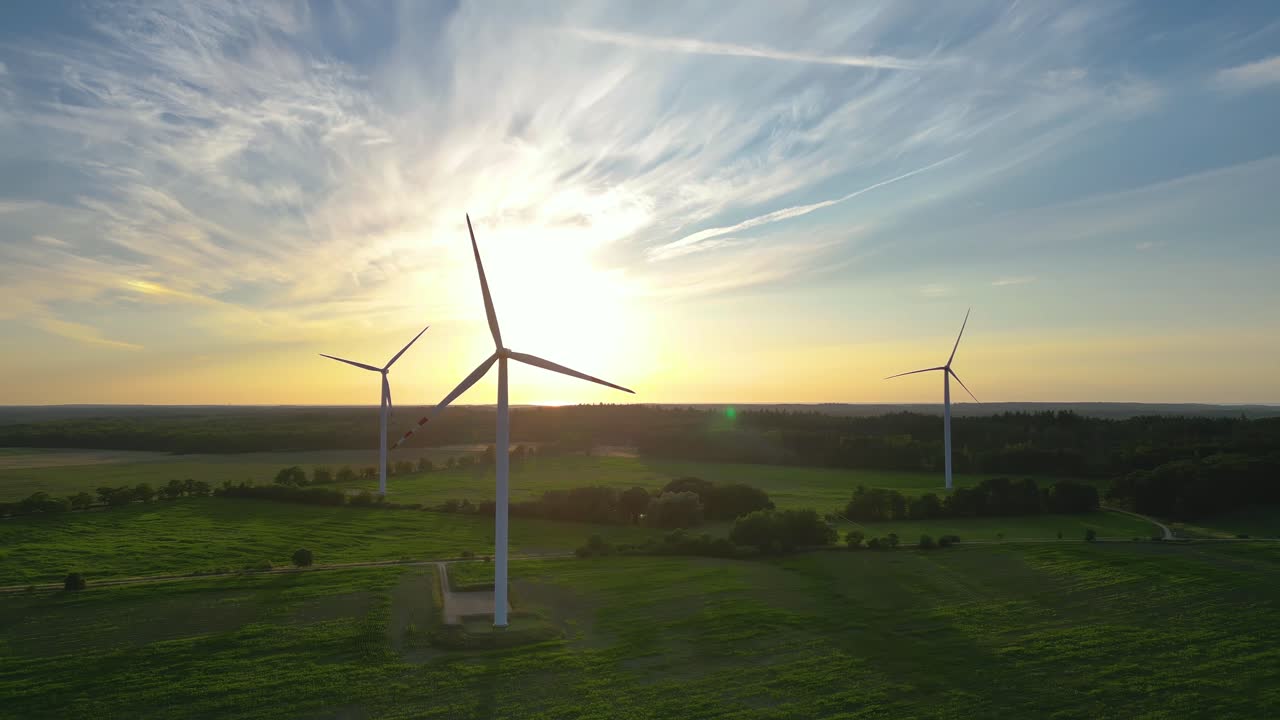 grandes turbinas eólicas con palas en el campo vista aérea puesta de sol naranja brillante cielo azul parque eólico cámara lenta giro de drones