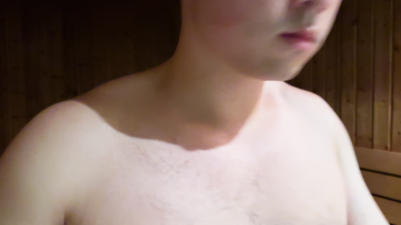 아시아 밀레니엄 남자가 에어을 착용하고 전화를 사용하고 나무 사우나에서 나갑니다.