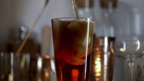 soda en cámara lenta vertiendo en un vaso de pinta con hielo