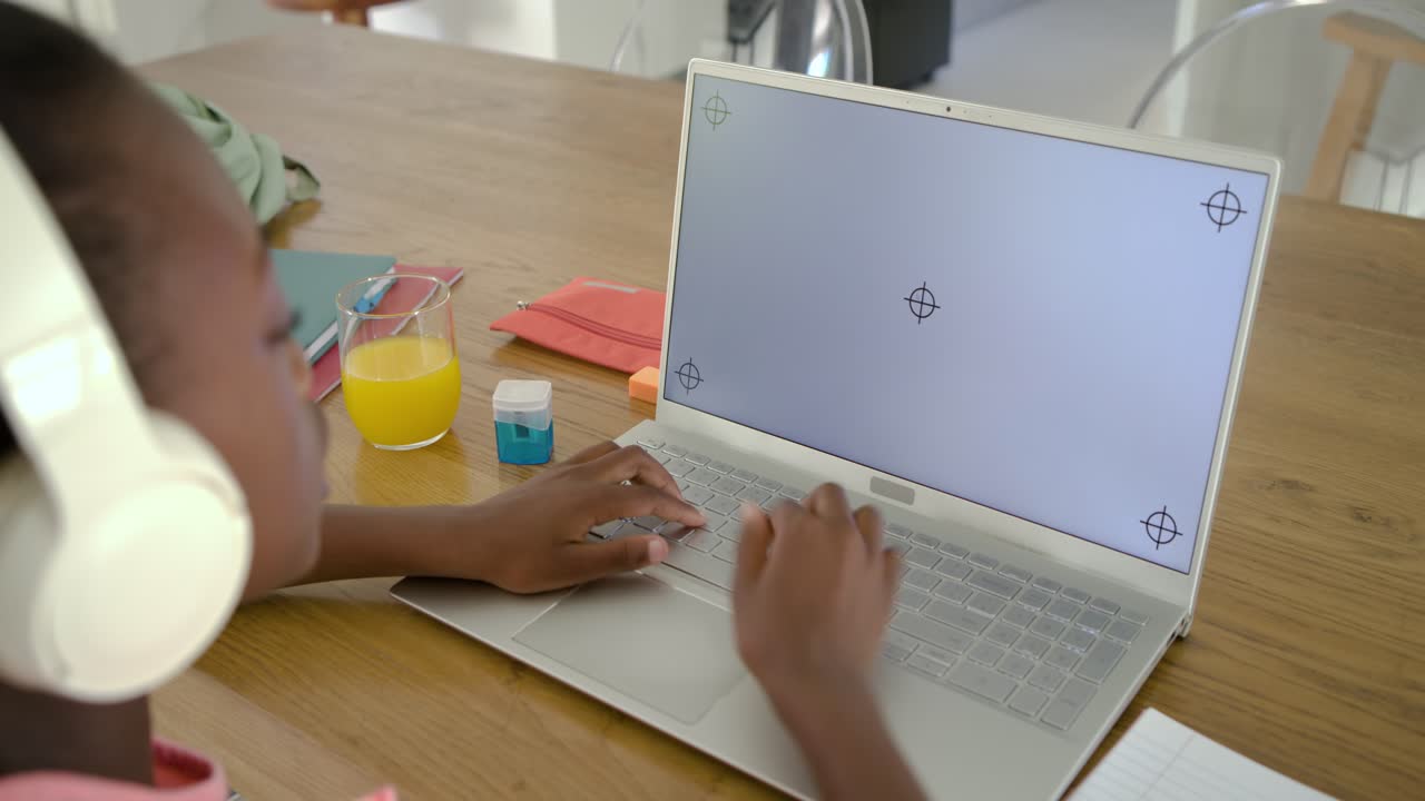 Adolescente com fone de ouvido digitando no laptop à mesa da cozinha, respondendo a uma tela em branco, com espaço para texto