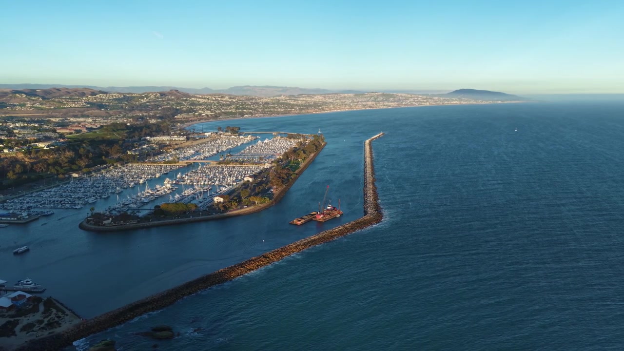 Vista Aérea Panorâmica do Porto de Dana Point ao Pôr do Sol. Localizada na costa da Califórnia, no Condado de Orange, esta bela imagem revela as águas costeiras azuis do Pacífico