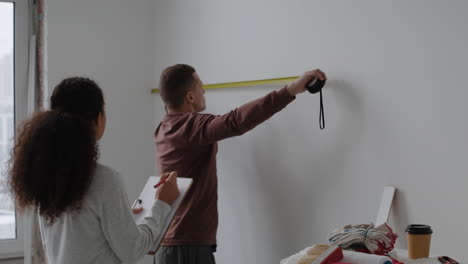 couple measuring wall for home renovation project