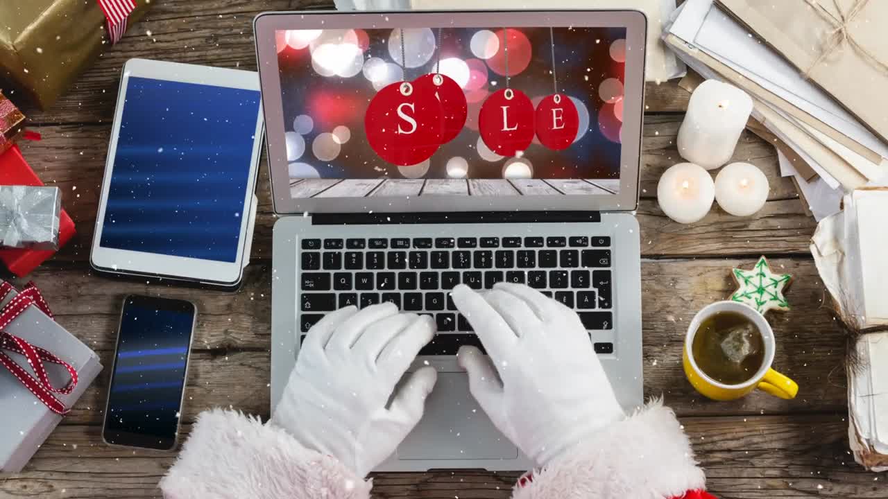 composición de video con nieve sobre el escritorio con la mano de santa en la computadora portátil