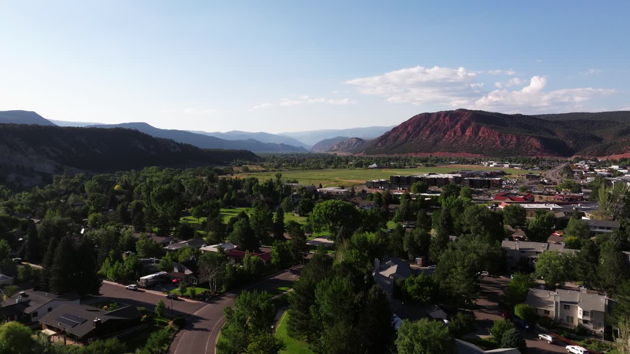 Drone dolly across Carbondale revealing broad valley plains in soft morning light, establishing aerial through neighborhood