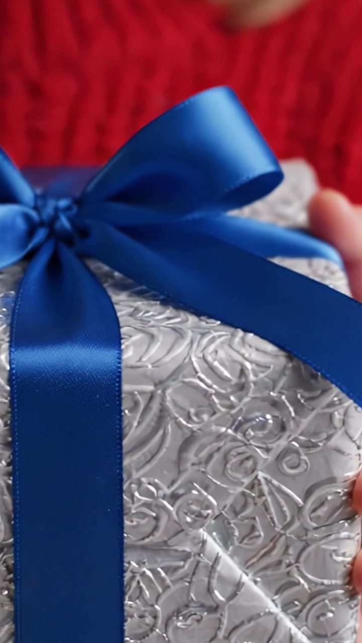 Regalo splendidamente incartato con nastro blu: un primo piano che cattura il design intricato e l'eleganza del dono, perfetto per ogni celebrazione o occasione speciale