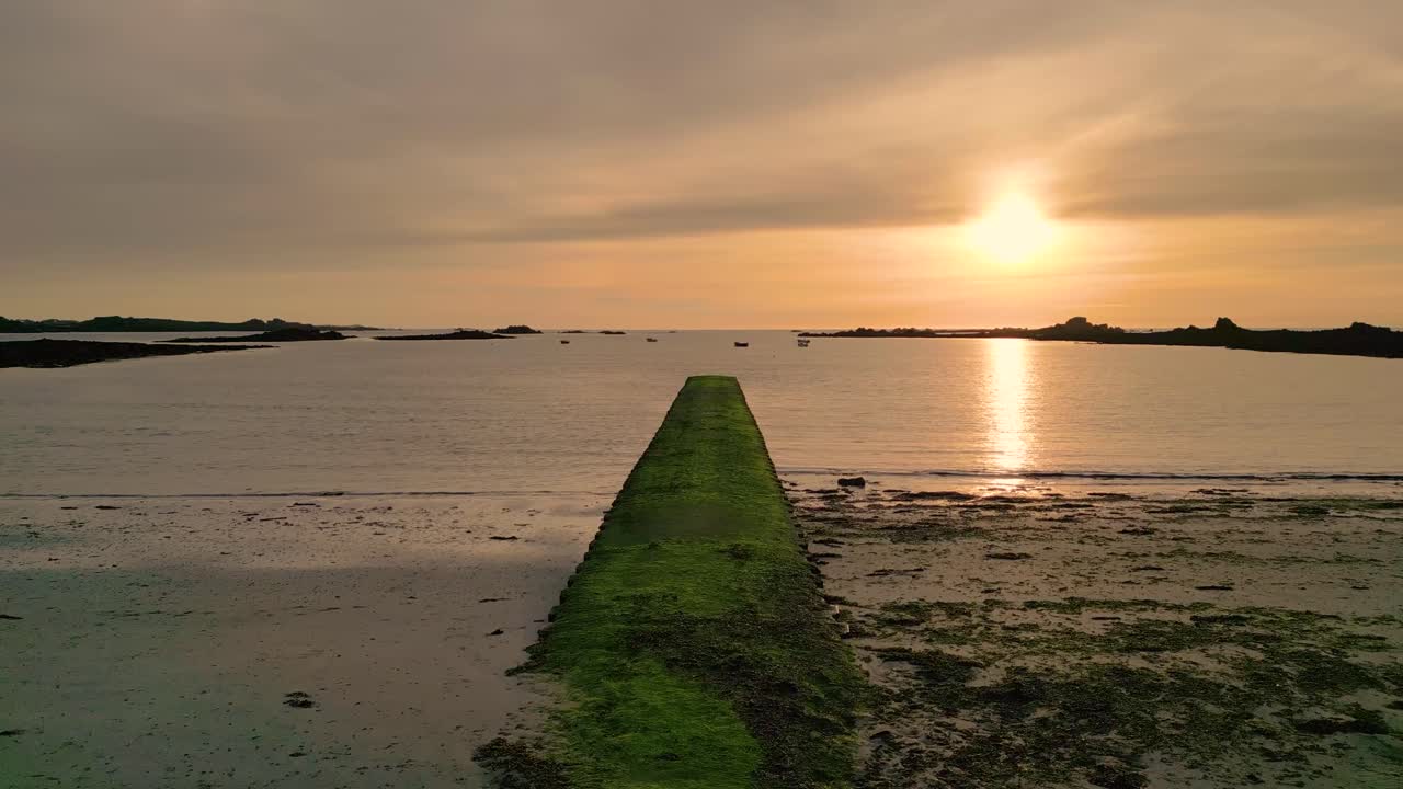 Sunset over Cobo Bay Guernsey slow flight over jetty and beach at mid tide into the sunset with boats at anchor and golden sky