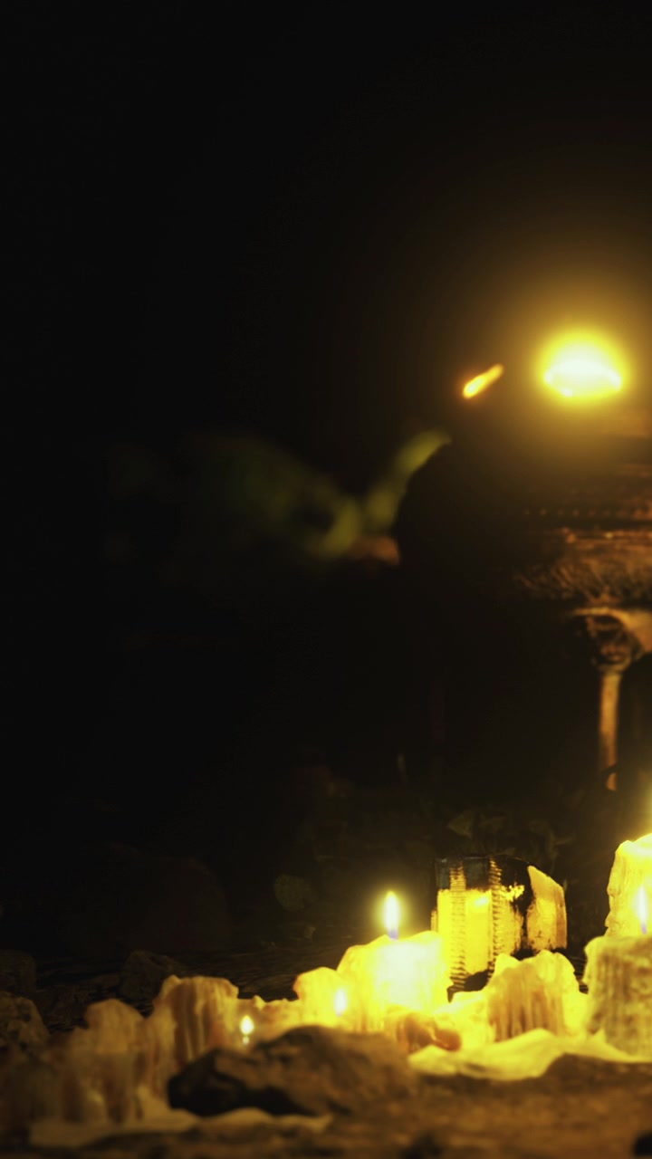 Candele brillano vicino a una statua di notte in un ambiente buio