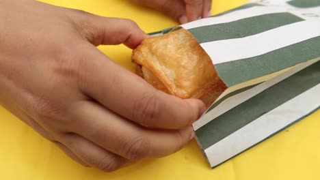 delicious pastry in a green and white striped paper bag