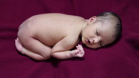 newly-born-baby-laying-on-red-velvet-cloth-with-cute-facial-expression-from-different-angle