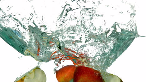 Apple-segments-plunging-into-water-on-white-background