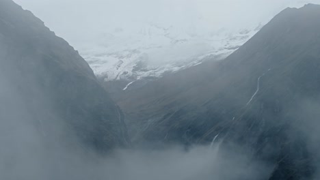 rugged rocky mountains background with copy space, atmospheric mood with moody mist and clouds, dramatic himalayas background with copyspace in muted desaturated nature background